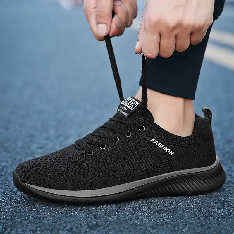 Men's Lightweight Running Sneakers in black being laced up, perfect for casual and sporty looks.